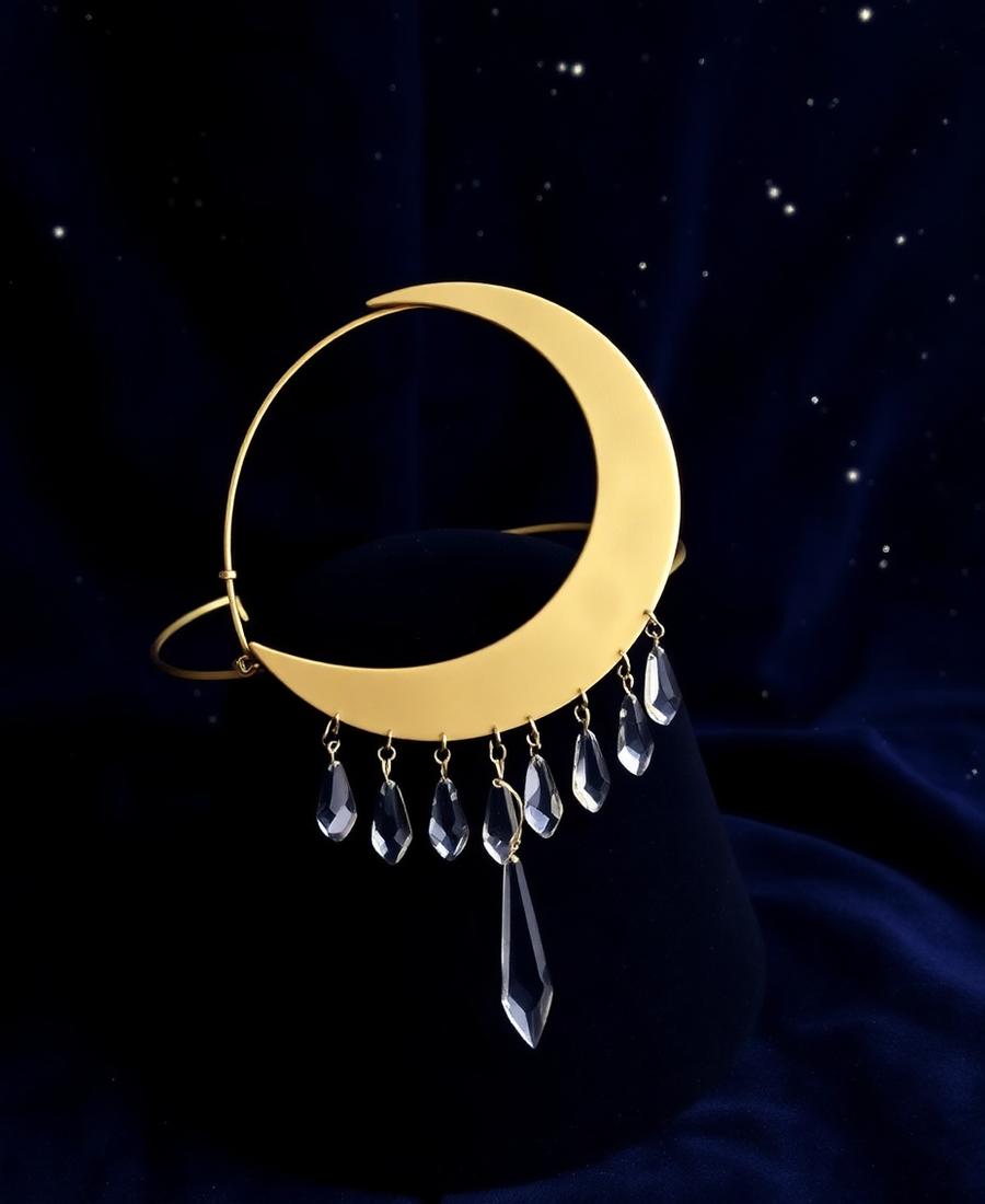 Gold crescent moon headpiece with hanging clear crystal drops against a starry navy backdrop