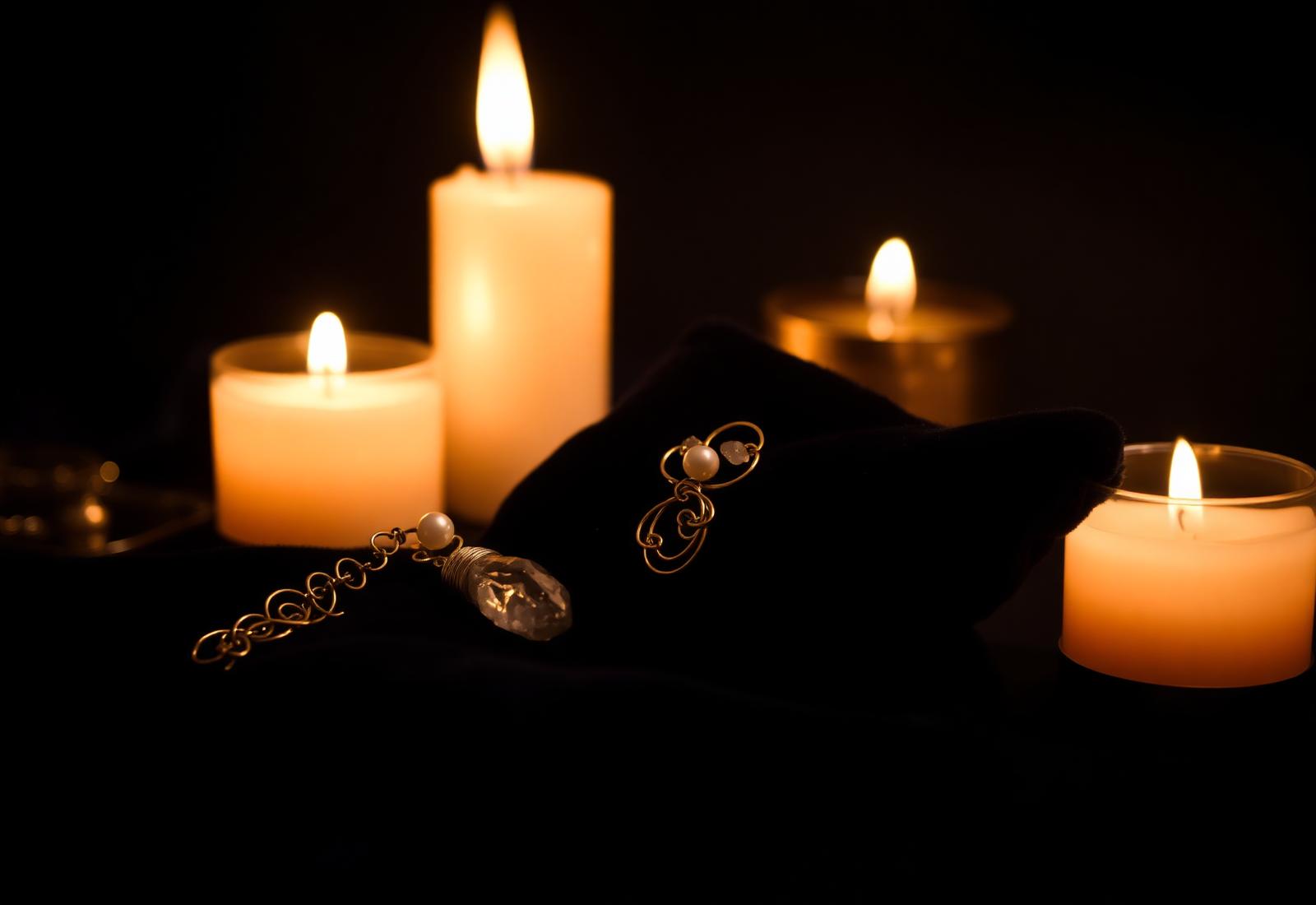 Handcrafted gold wire jewelry with pearls and quartz on dark velvet in candlelight
